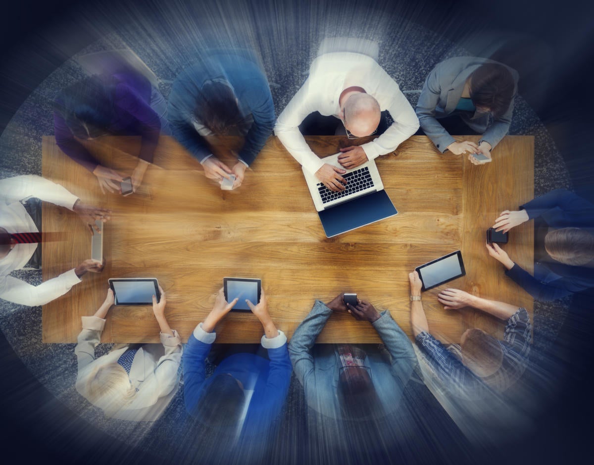 Group of workers collaborating around a table with mobile devices