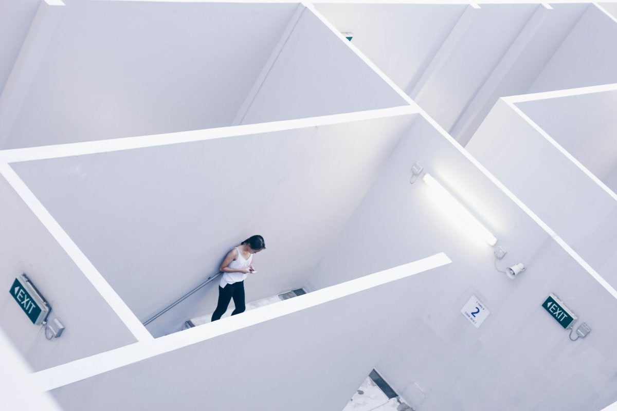 woman in an office stairwell near exit signs [by Andrew Loke - CC0 via Unsplash]