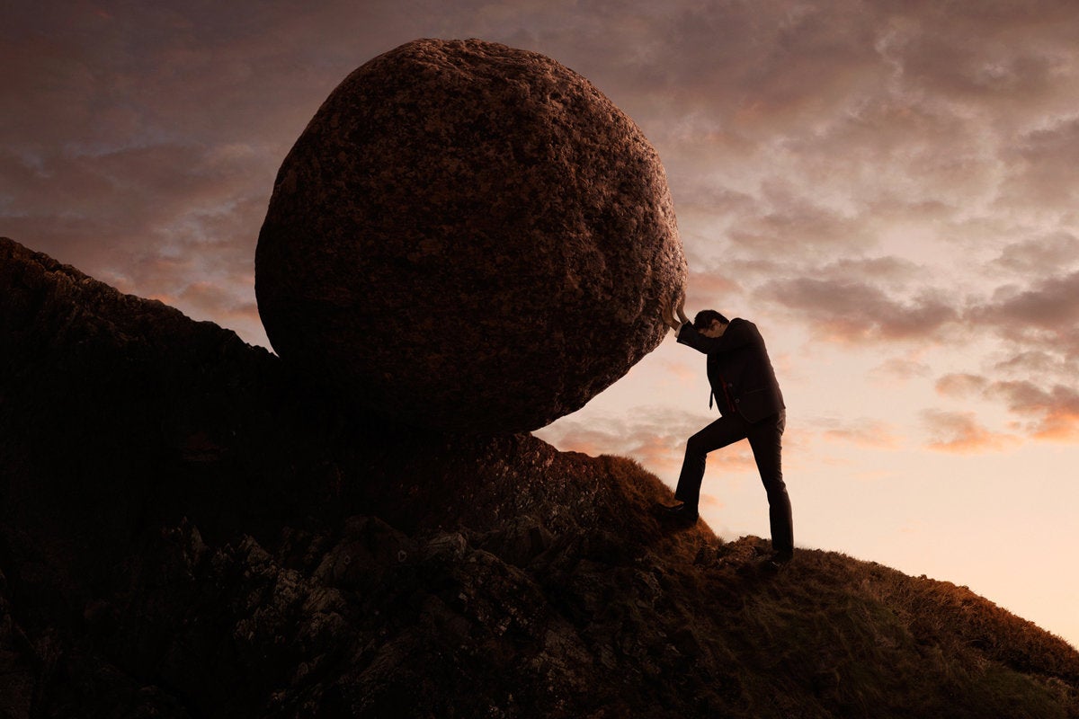 executive pushing boulder uphill deadline stress struggle