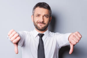 man holding thumbs down dislike disapprove