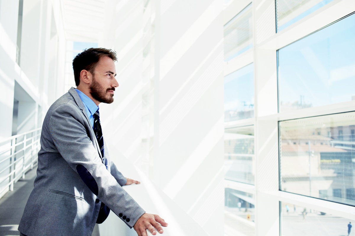 young executive in office atrium reflecting thinking