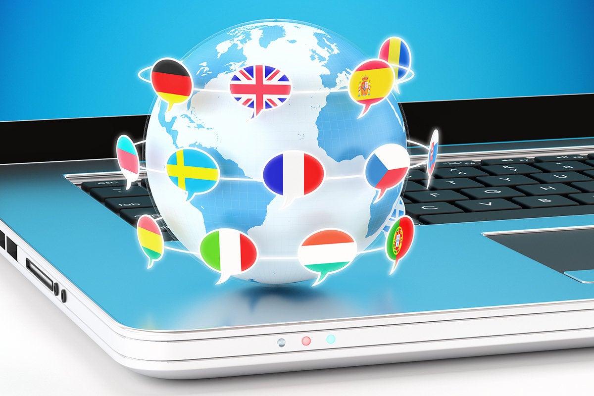 Globe with orbiting speech bubbles containing world flags, sitting on the edge of a laptop.