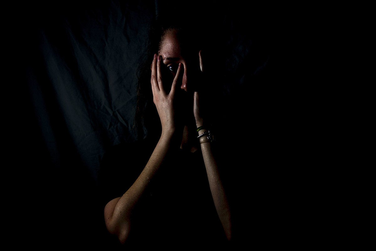 fearful woman covers her face with her hands / afraid / distressed