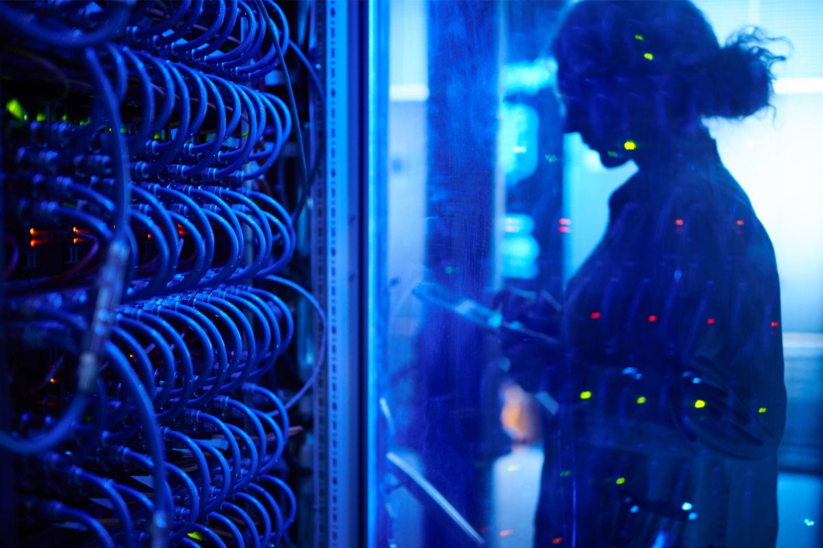 woman technician in network room looking at server