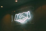 Neon sign > handshake / deal / agreement / partnership / team / merger