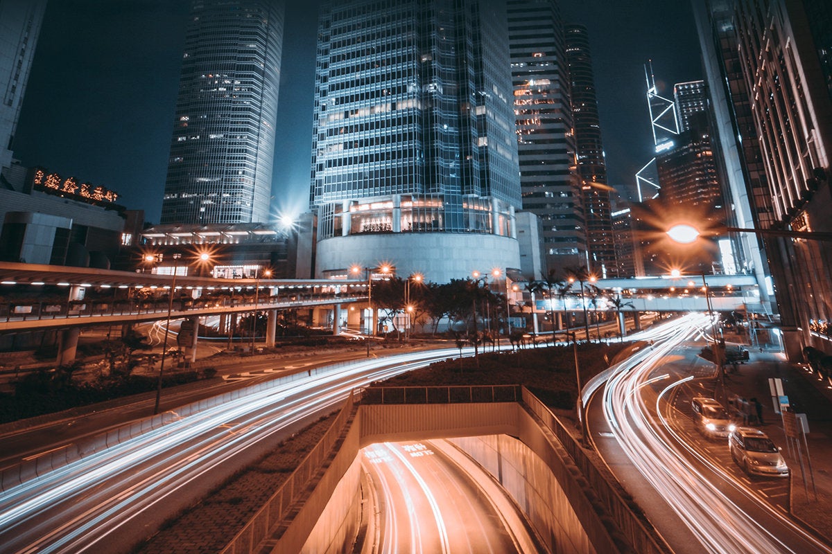 Hong Kong / long exposure traffic near IFC skyscrapers at night / speed / connections / smart cities