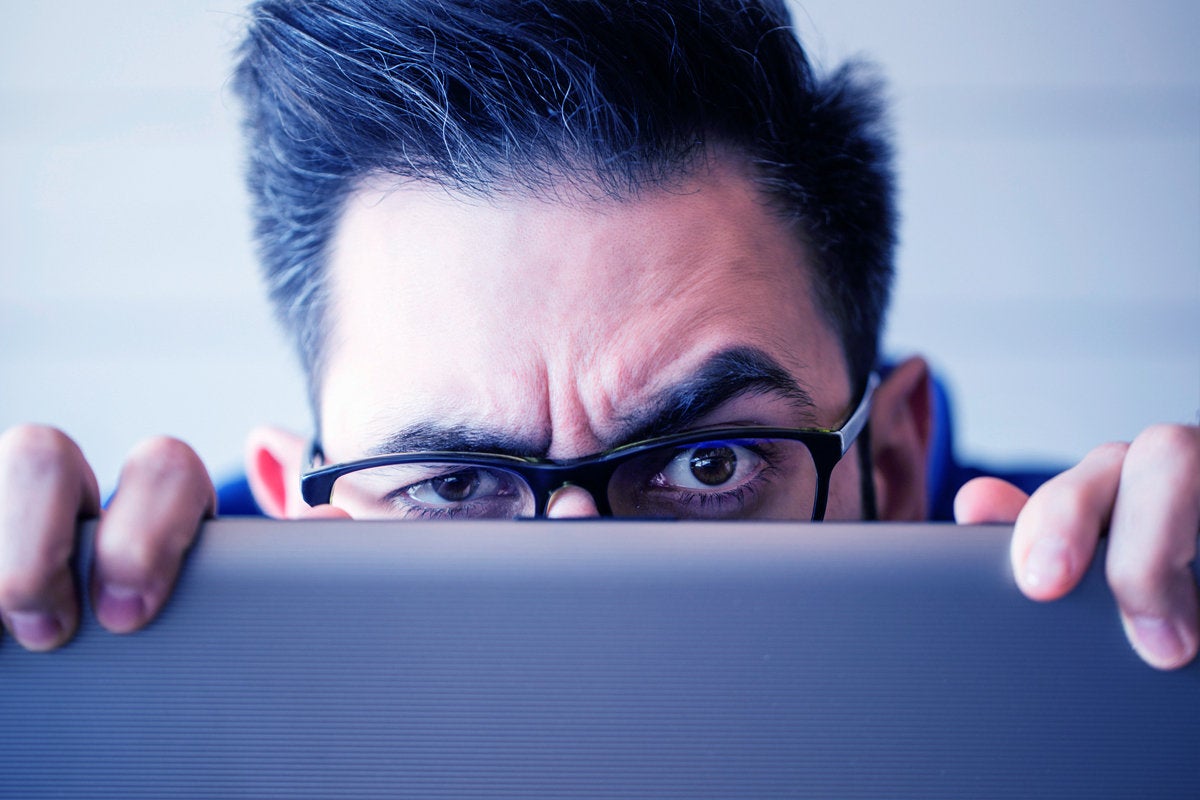 2 acceptable use man hiding behind laptop computer sneaky employee hiding