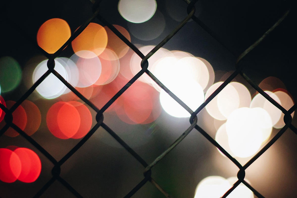 blurred city view beyond wire mesh fence / mesh network