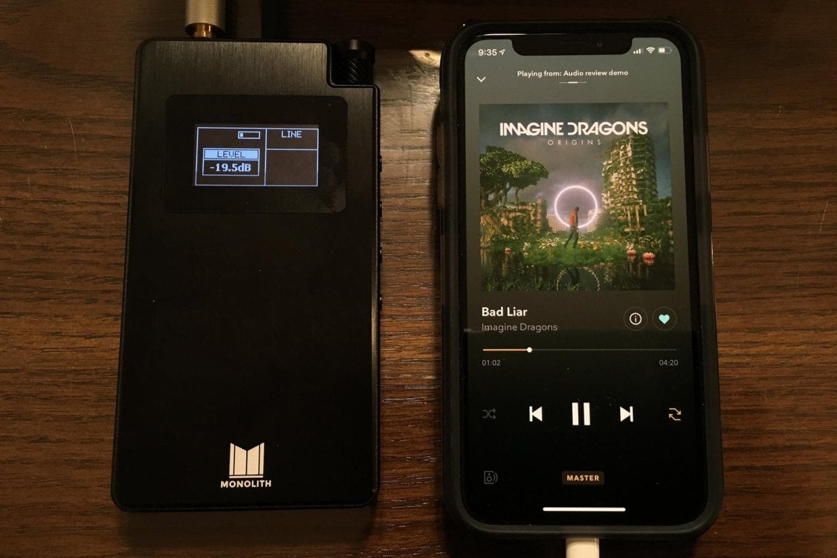The Monolith portable headphone amplifier connected to an iPhone XS. The two are comparable in size.