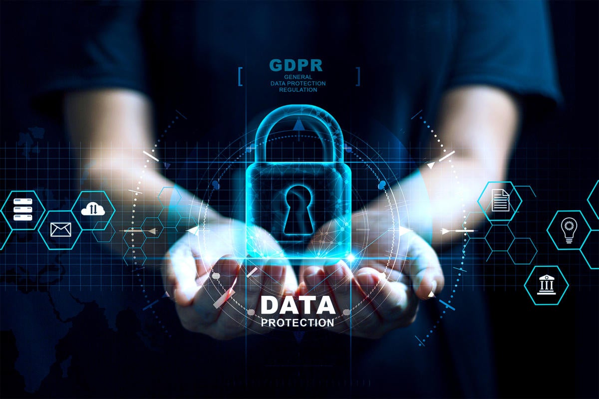  A person in a black shirt is holding a glowing blue padlock with the text 'Data Protection' in front of their chest with various data icons surrounding them.