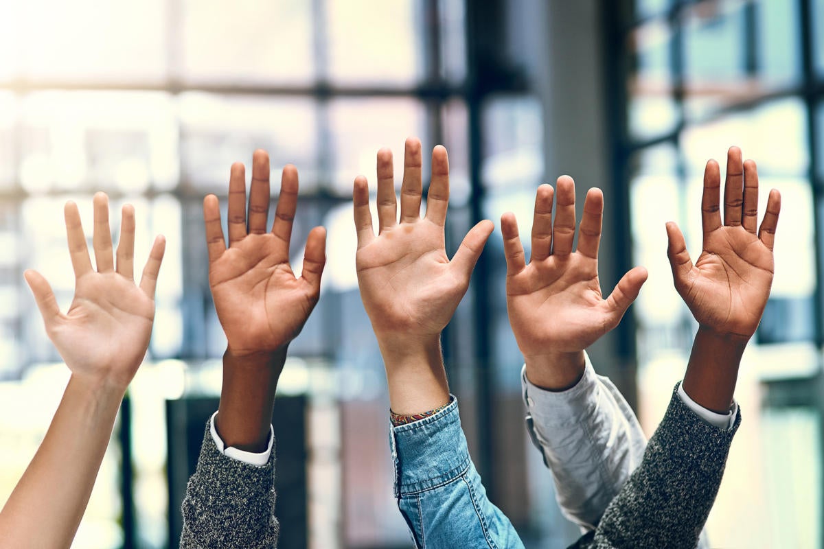 Volunteers / volunteerism  >  A group of business people raises their hands.