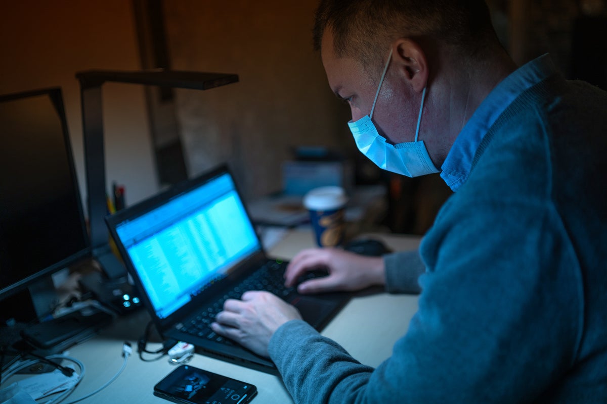 A laptop user wears a mask as protection from viruses, pollutants, toxins / COVID-19 pandemic