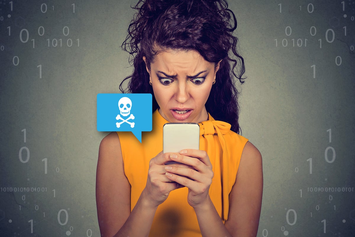 Smishing  >  A woman looks at her mobile phone in horror when receiving a malicious SMS text message