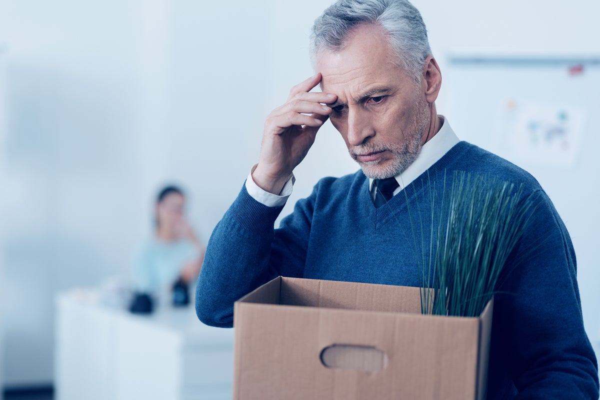 Layoffs  >  A stressed businessman carries away his personal belongings in a cardboard box.