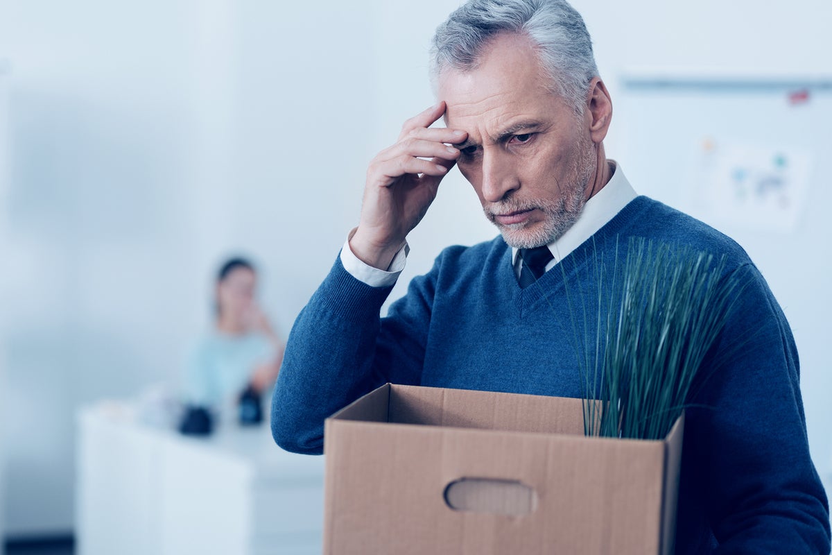 Layoffs > A stressed businessman carries away his personal belongings in a cardboard box.
