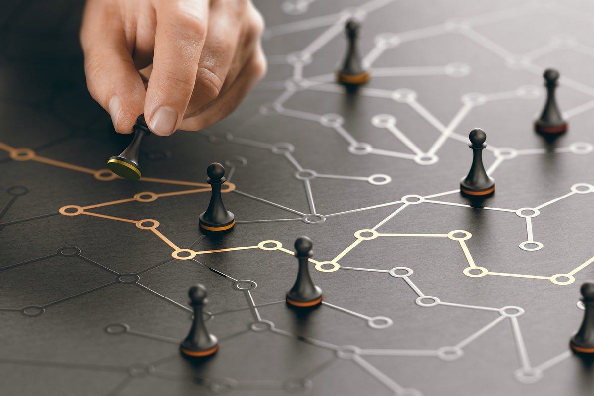 A hand moves a pawn through a conceptual maze of circuits. [navigating/negotiating/strategy/tactics]