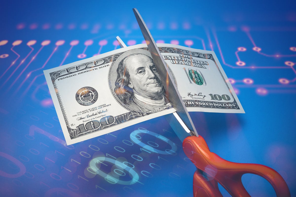 Scissors cutting through a hundred-dollar United States banknote