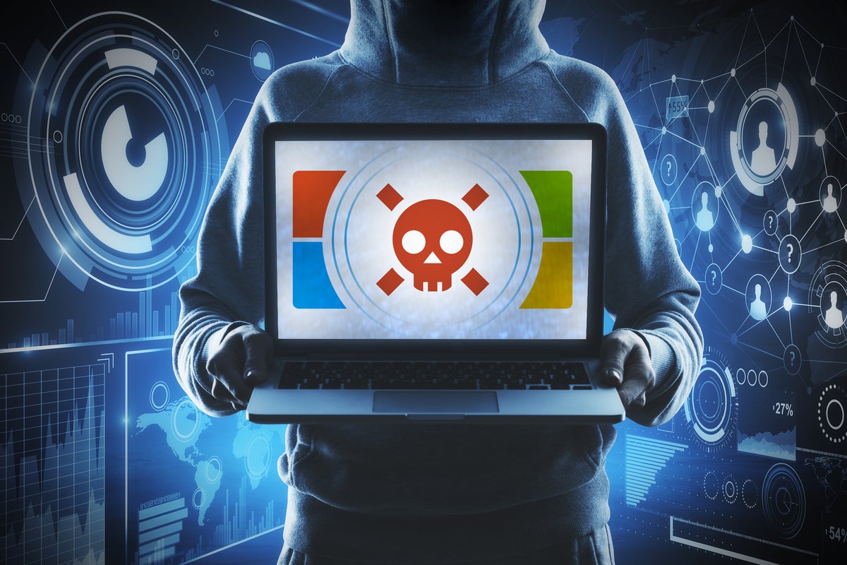 A hacker with laptop diplays a skull and crossbones with Microsoft colors.