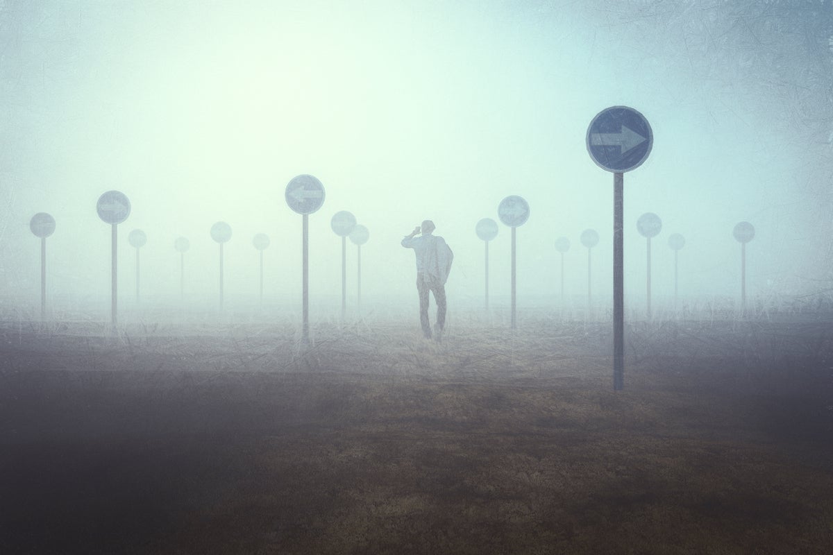 A lost businessman wanders amid conflicting directional signs through the fog.