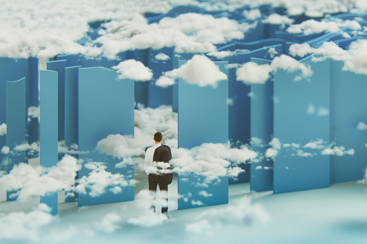 A businessman stands in front of maze strewn with clouds.