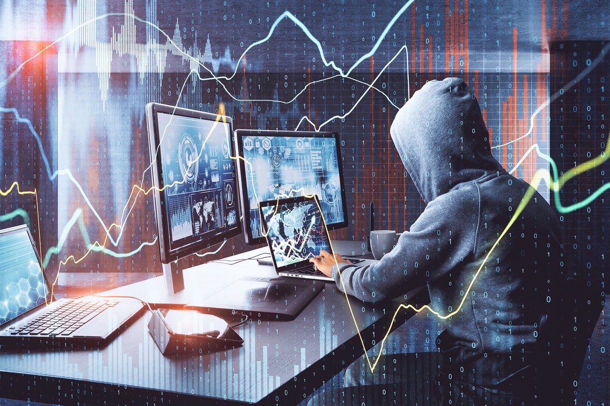 An anonymous hooded laptop user is surrounded by binary code and graphed data. [security threat]