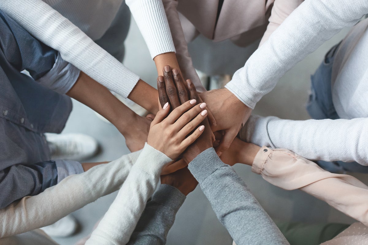 Team member extends all hands in for a huddle. [unity / teamwork / trust / diversity / inclusion]