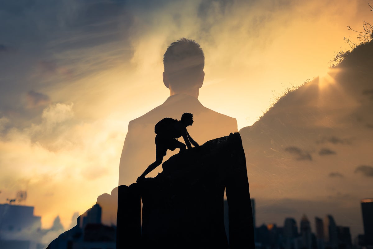 Multiple-exposure image of a businessman's silhouette against an image of him climbing a mountain.
