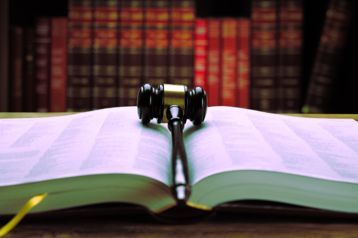 A gavel rests on open law book. [law / regulation / compliance / legal liability]