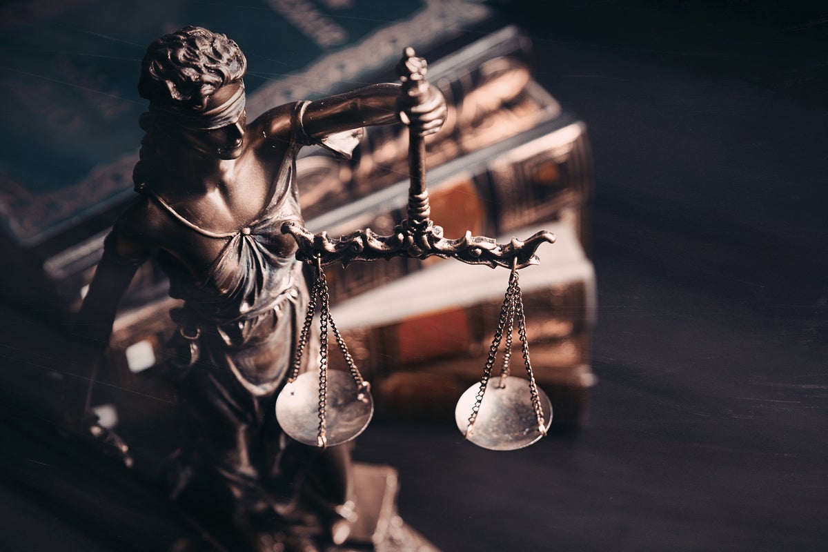 Lady Justice statue with scales, law books. [regulation / compliance / legal liability / fairness]