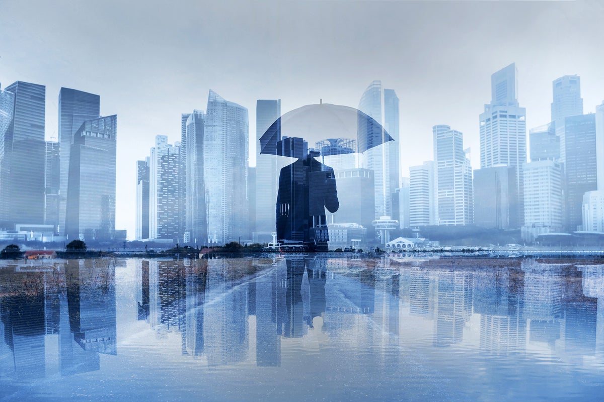 A man with an umbrella appears waist-deep in water against a city skyline. [multiple-exposure]