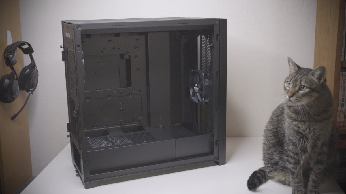 5000D Airflow without main side panel sitting at angle on table, with black tabby cat sitting nearby