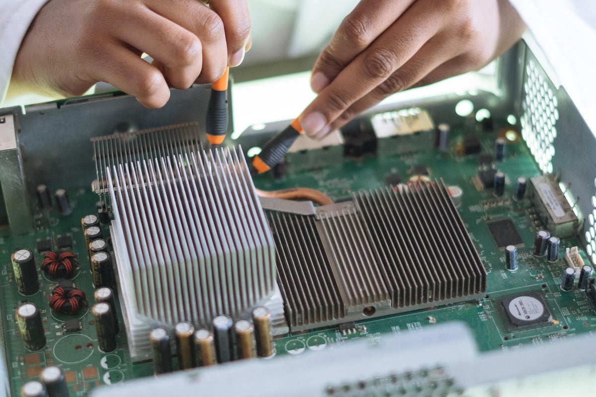 person performing maintenance on a motherboard