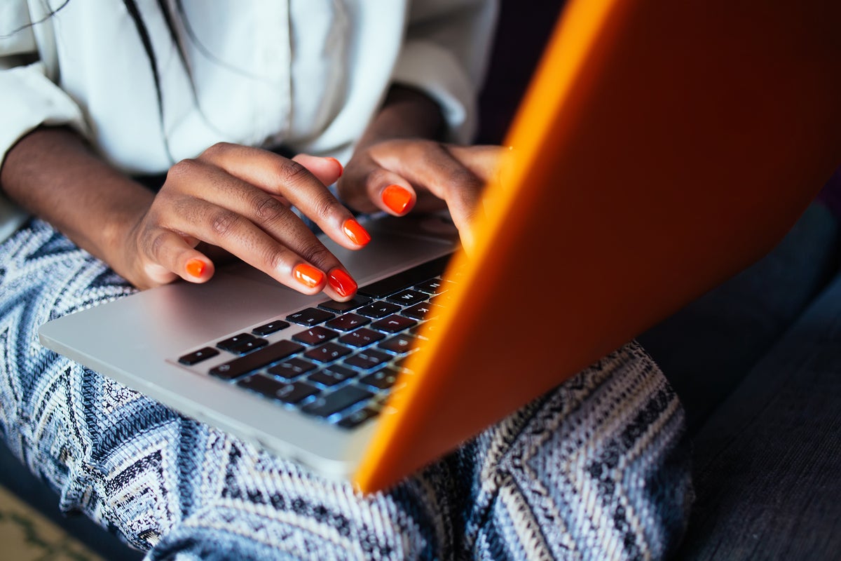 Hands type on a laptop keyboard.