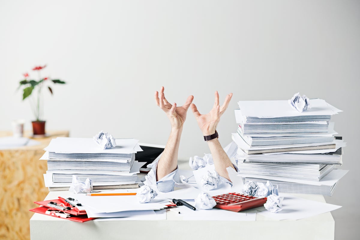 Many crumpled papers on desk of a stressed male employee