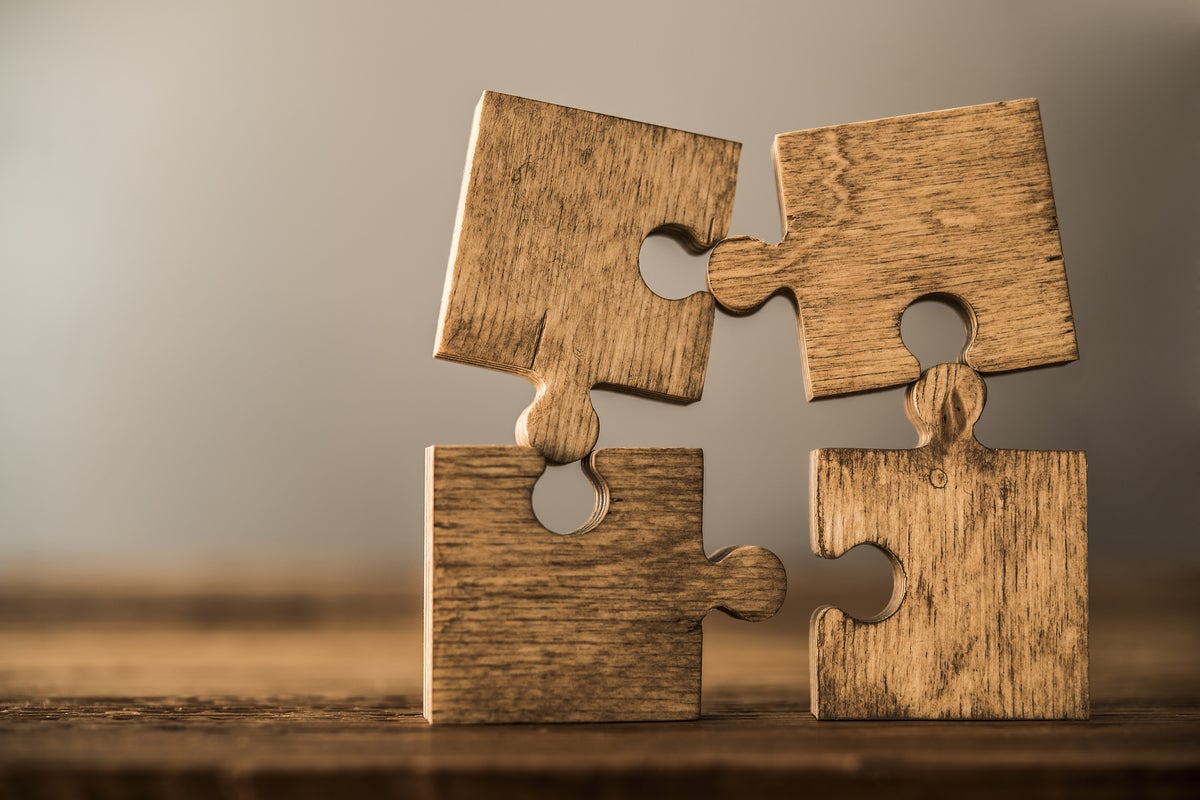 Four brown pieces of puzzle stand on wooden table representing integration