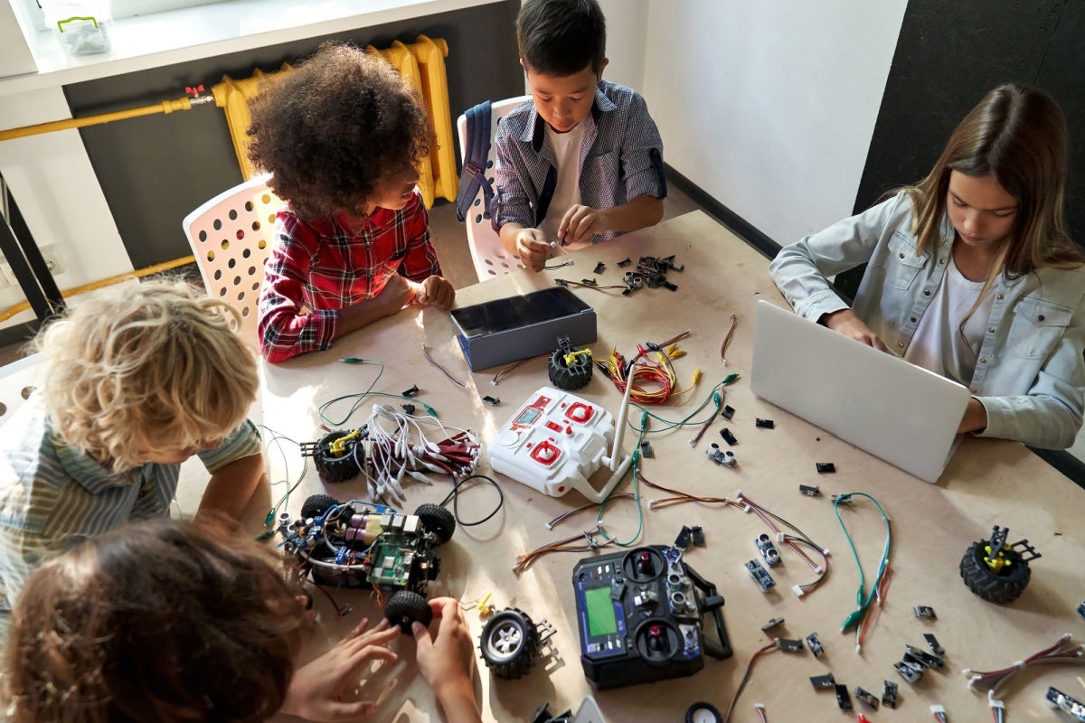 Table top view of multicultural schoolchildren building robots – STEM education concept