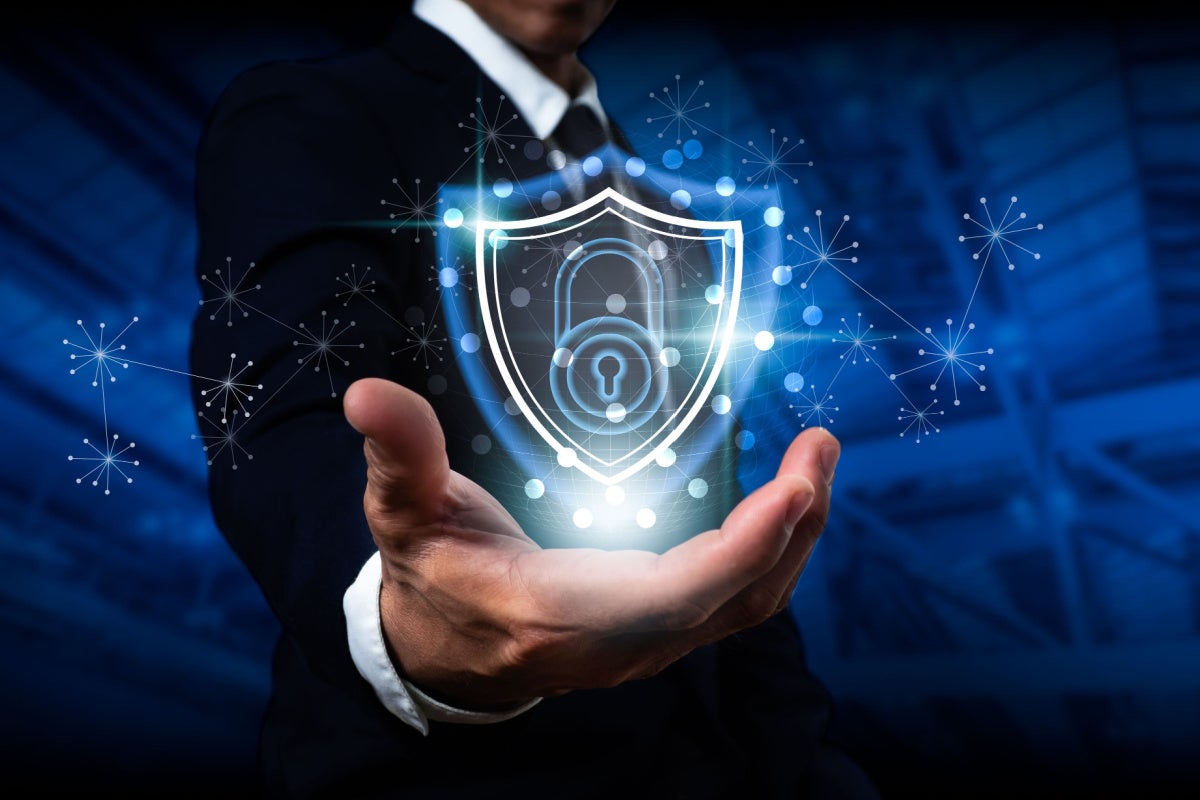 Businessman holding a shield with a padlock, threat protection concept