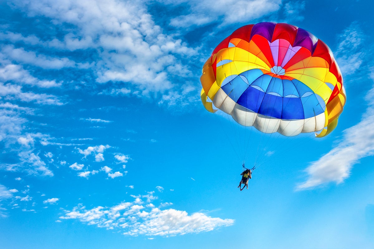 shutterstock 1018105807 rainbow colored parachute against a blue sky and cirrus clouds