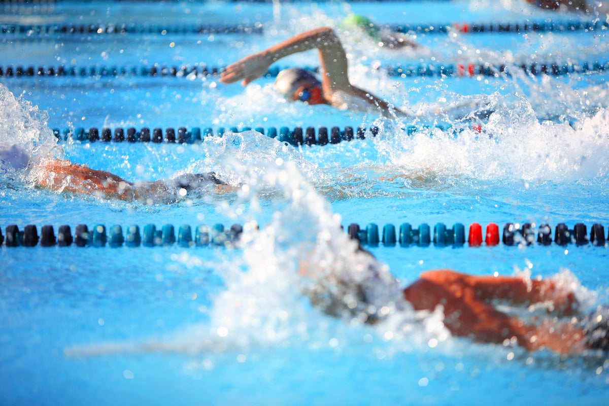 Swimmers racing in three swimming pool lanes.