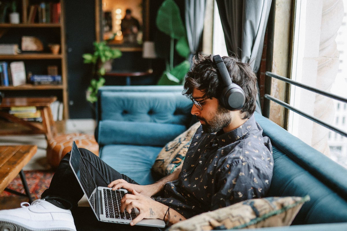 Man with headphones working on a laptop in a room