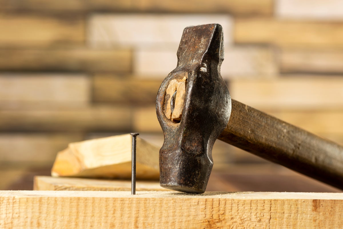 shutterstock 1887035158 hammer and nail on a wooden board