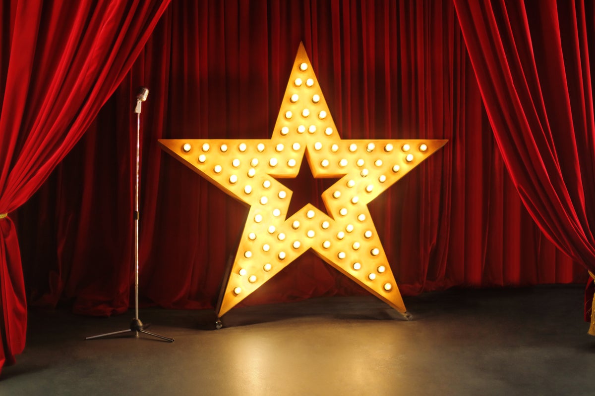shutterstock 218547988 retro stage with red curtains standing mic and giant gold star with lights