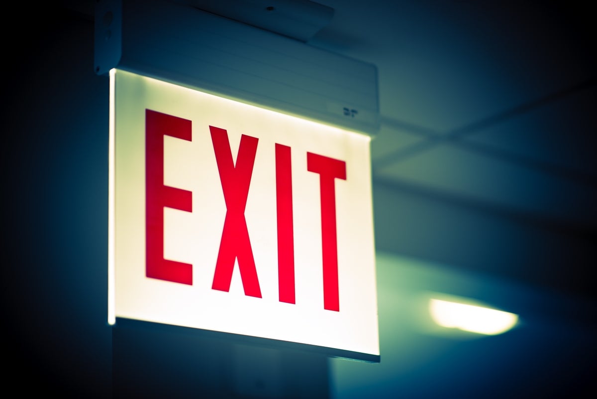 shutterstock 290597015 brightly lit exit sign in dim office corridor