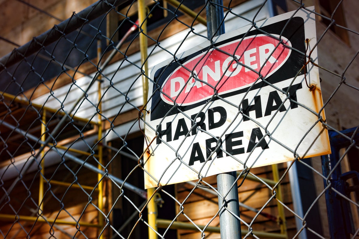 shutterstock 77002051 Danger hard hat area safety warning sign chain link fence construction site