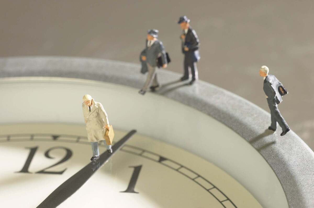 Conceptual photo of toy businessmen walking on clock