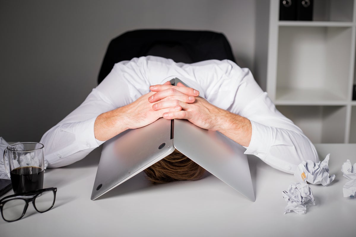 Man hiding under laptop in frustration because of mistakes, failure