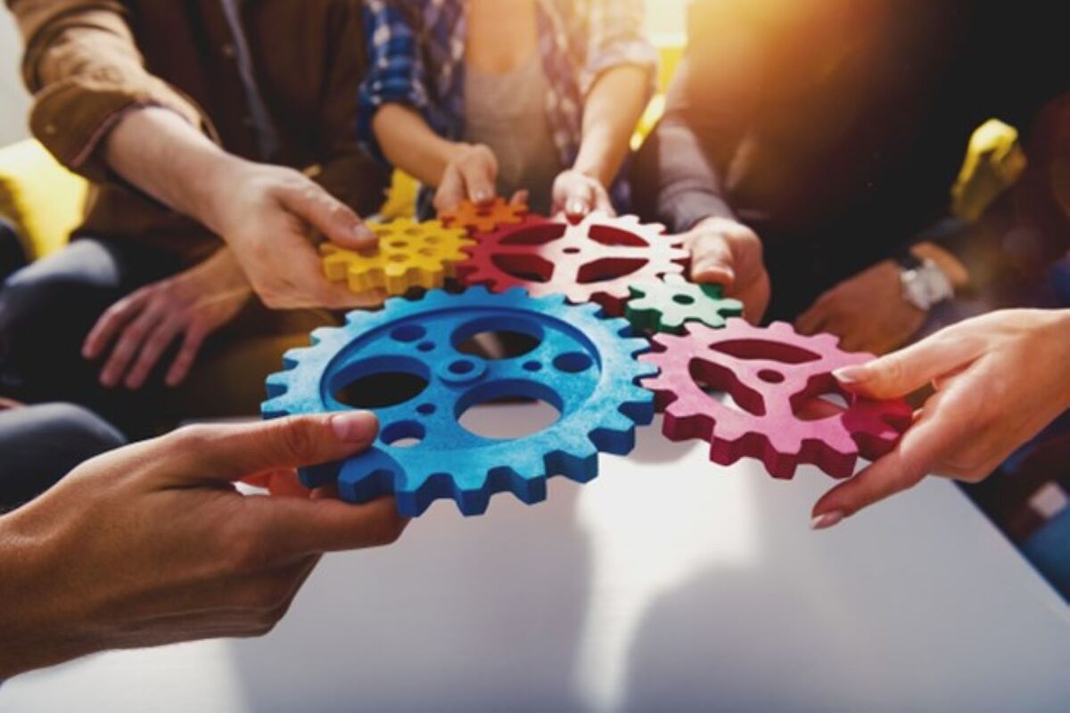 group of hands holding together multi colored gears