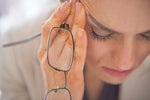 Closeup on stressed business woman with eyeglasses -- tension headache burnout
